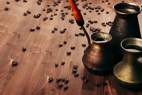 قهوه داغ در گلدان‌های ترکی عتیقه گروهی با خامه دانه‌های تاری روی پس‌زمینه تخته چوبی قدیمی قهوه‌ای سبک روستیک