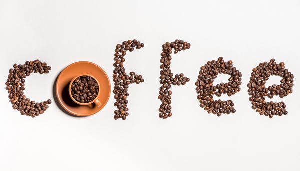 نمای بالای قهوه کلمه ساخته شده از دانه های قهوه و فنجان با دانه های قهوه