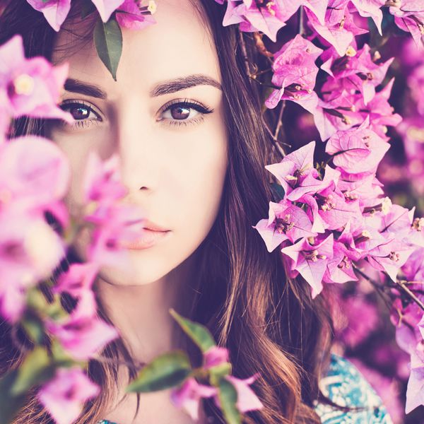 زن جوان زیبا که با گل احاطه شده است