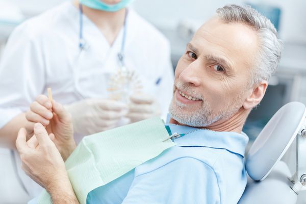 بیمار بالغ هنگام مراجعه به دندانپزشک به نمونه دندان نگاه می کند