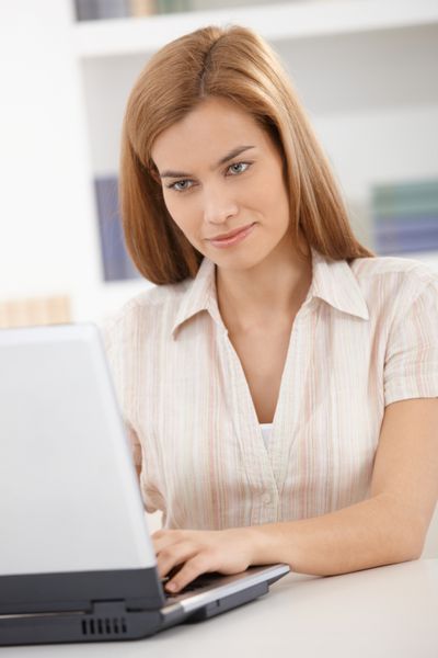 پرتره زن جوان با استفاده از لپ تاپ در حال لبخند زدن