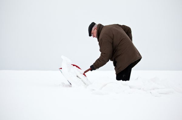مردی که با بیل برف را برمی دارد