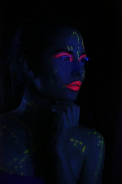 زن درخشان با پوشیدن لوازم آرایشی UV زیر نور سیاه