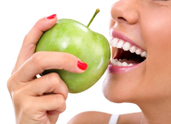 نمای نزدیک از صورت زنی در حال خوردن سیب سبز