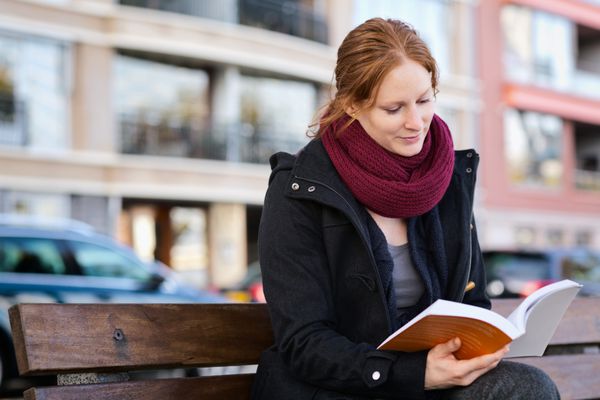 زنی در حال خواندن کتاب در شهر