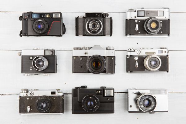 مجموعه ای از دوربین های فیلم قدیمی روی میز چوبی