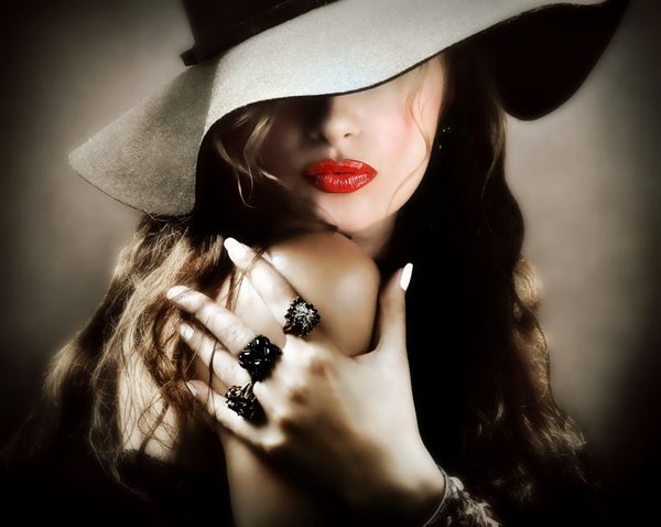 مدل زن جوان زیبا با لب‌های قرمز کلاه قدیمی قدیمی و جواهرات در حال ارسال یک بوسه است - نمای نزدیک