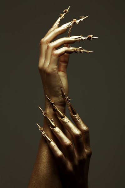 مفهوم مانیکور هنری دست های طلایی زیبا با ناخن های بلند طلایی نزدیک شات استودیویی