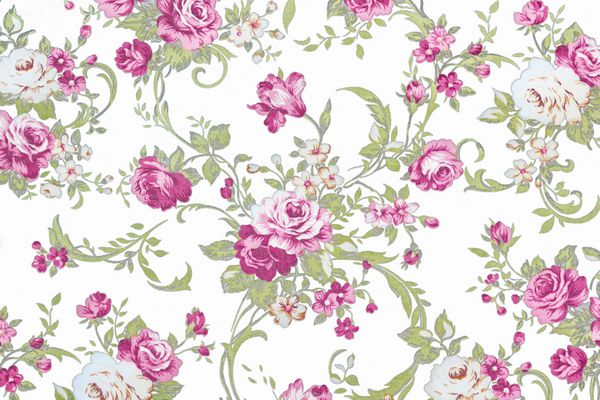 گل رز صورتی روی زمینه پارچه سفید تکه ای از الگوی پارچه ملیله رنگارنگ رترو با تزئینات گلدار که به عنوان پس زمینه مفید است