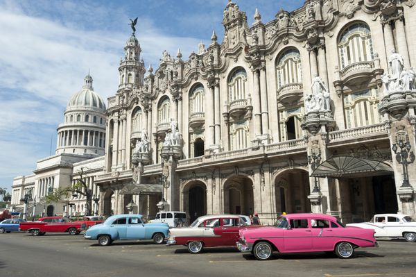 ردیفی از اتومبیل‌های آمریکایی با رنگ‌های روشن در خیابان مقابل کاخ گالیسی در خیابان پرادو در مرکز هاوانا کوبا پارک شده‌اند