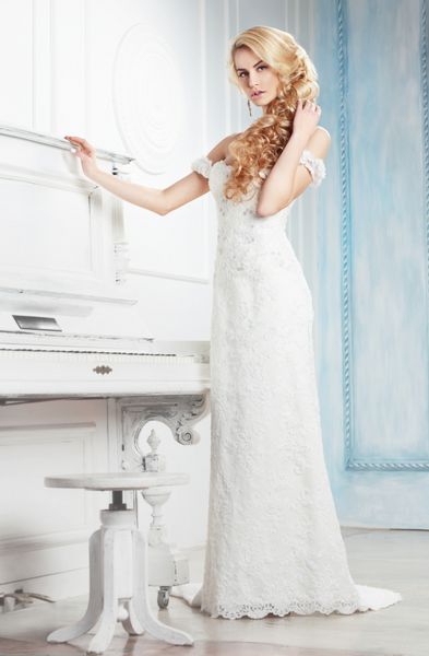 عروس با لباس سفید در کنار پیانو ژست گرفته است