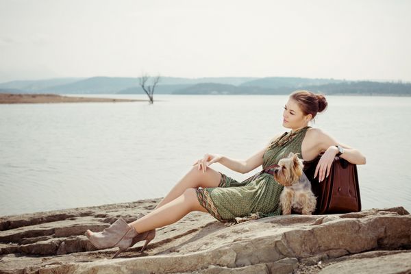 عکس مد از یک مدل زیبا و حرفه ای در دریاچه با یک چمدان و یک سگ Yorkshire Terrier