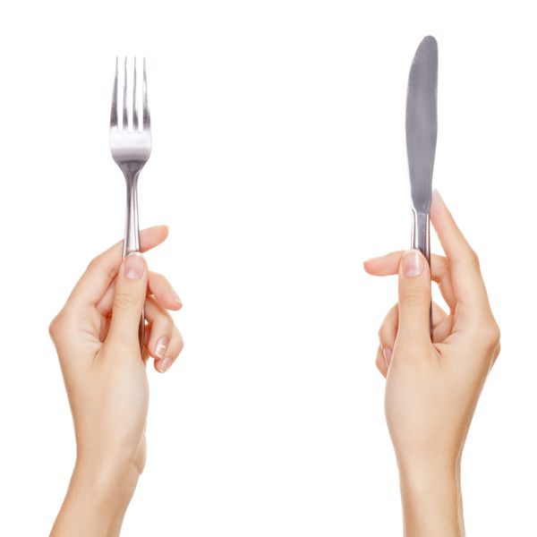 چاقو و چنگال که در دستان زن گرفته می شود جدا شده روی سفید