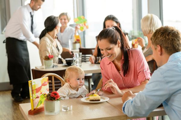 زن و شوهر در حال غذا دادن به کیک به فرزندشان در کافه رستوران زن مرد