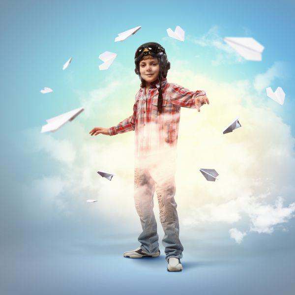 تصویر پسر کوچک با کلاه خلبانی با هواپیماهای کاغذی در پس زمینه