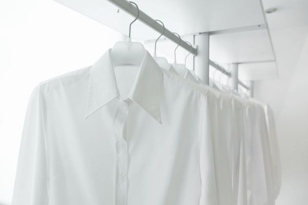 پیراهن های سفید آویزان در قفسه در کمد توکار