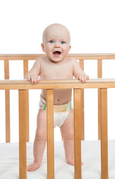 نوزاد پسر نوزاد در حال فریاد زدن یا فریاد زدن در پوشک در تخت چوبی در زمینه سفید