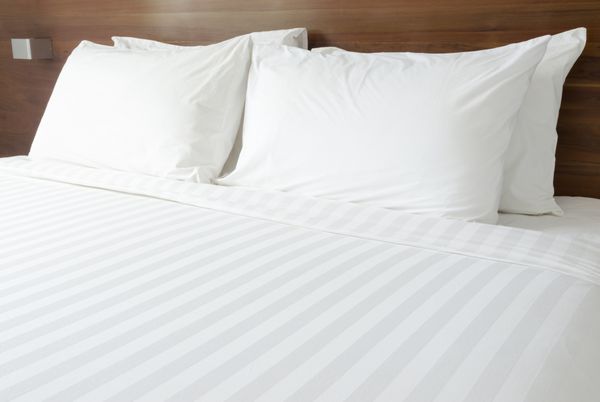بالش های سفید روی تخت بالش های نرم راحت روی تخت