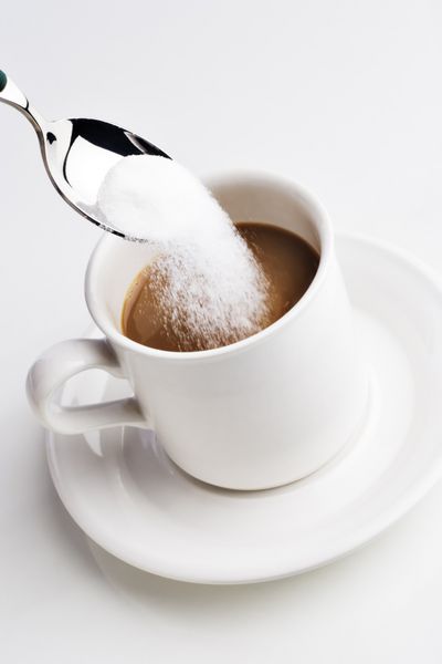 با قاشق شکر را در یک فنجان قهوه بریزید