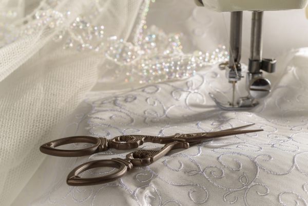 قیچی آنتیک در برابر مواد لباس عروس و چرخ خیاطی