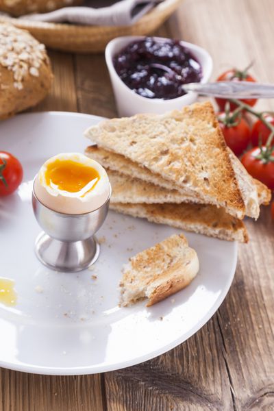 تخم مرغ نرم صبحگاهی با فلفل گوجه فرنگی و کروتون در پس زمینه مربا شیره و نان عکس dSLR