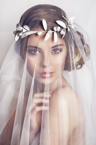 عروس زیبا با مدل موی عروسی مد - در پس زمینه سفید پرتره نزدیک از عروس جوان زرق و برق دار عروسی عکس استودیو پرتره عروس زیبا با حجاب روی صورتش