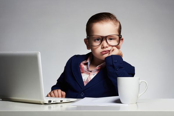 شغل خسته کننده پسر جوان تاجر کودک بامزه با عینک خودکار نوشتن رئیس کوچک در دفتر