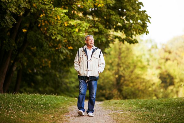 مرد مسن شاد در حال قدم زدن و استراحت در پارک