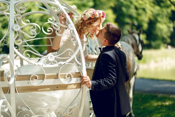 زوج عروسی رمانتیک افسانه ای عروس و داماد در حال بوسیدن در کالسکه سفید سیندرلای جادویی