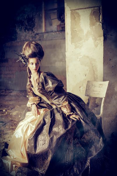 مد هنر زن جوان زیبا با لباس تاریخی زیبا و مدل موی باروکویی که در خرابه های قلعه ژست گرفته است رنسانس باروکو