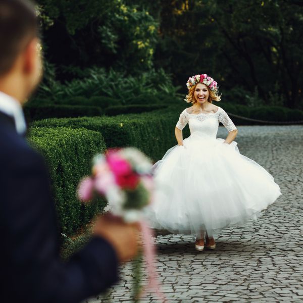 عروس زیبا و زیبا در حال دویدن به سمت داماد جذاب در فضای باز در پارک