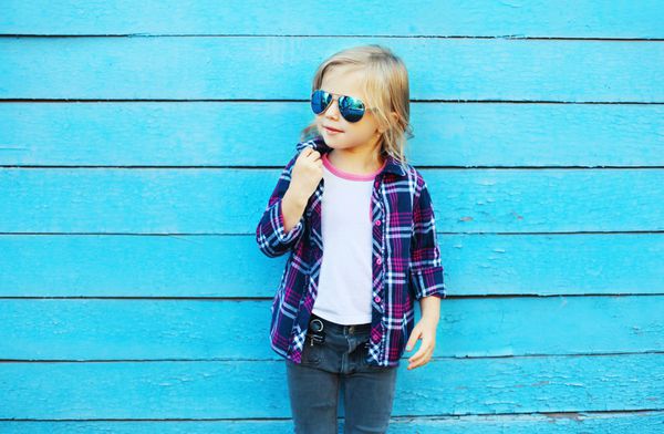 بچه مد در شهر کودک شیک با عینک آفتابی و پیراهن چهارخانه روی زمینه آبی نمای نمایه