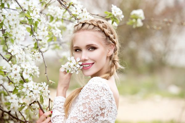 زن جوان زیبا در باغ شکوفه عروس