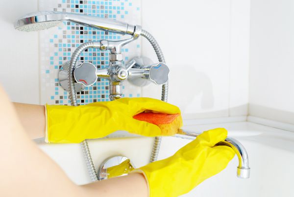 زنی در حال تمیز کردن حمام در خانه وان و شیر لباسشویی زنانه