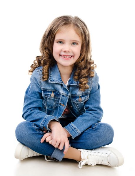 دختر کوچک خندان ناز روی زمین جدا شده روی یک سفید نشسته است