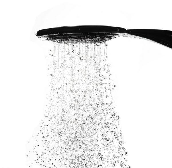قطرات آب از سر دوش در حمام در زمینه سفید حرکت توقف