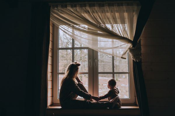 مادر با کودک کنار پنجره نشسته و بازی می کند