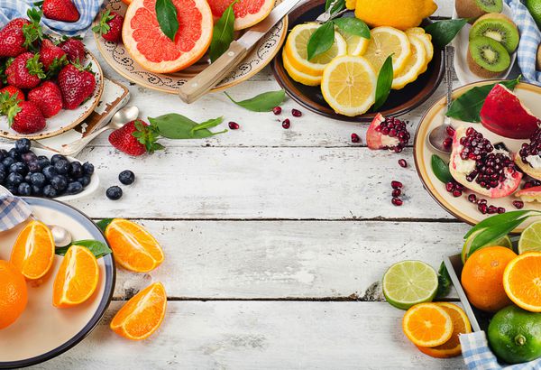میوه های تازه و انواع توت ها در زمینه چوبی سفید تغذیه سالم رژیم غذایی نمای بالا
