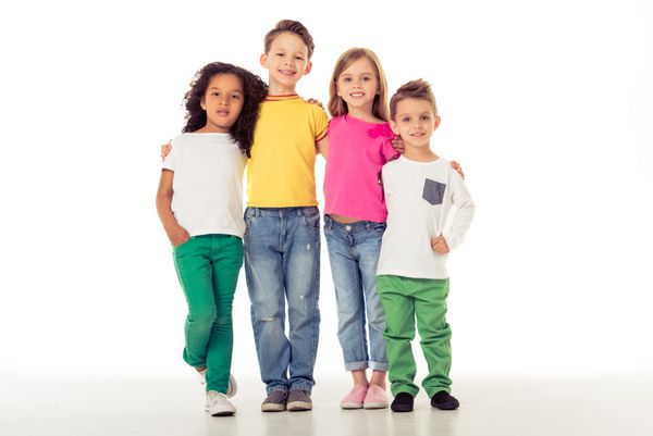 بچه‌های ناز با لباس‌های غیررسمی به دوربین نگاه می‌کنند و لبخند می‌زنند درحالی‌که دست‌هایشان را دور همدیگر ایستاده‌اند جدا شده روی پس‌زمینه سفید