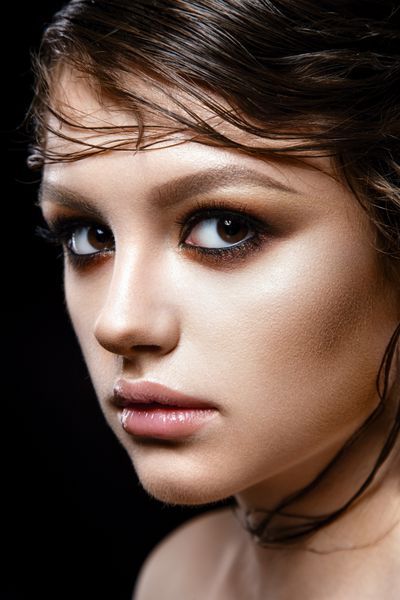 پرتره زن زیبا بانوی جوانی که از نزدیک در پس زمینه سیاه ژست گرفته است آرایش زرق و برق مدل موی زیبا