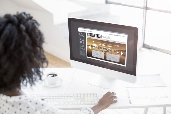 تصویر ترکیبی از رابط ساخت وب سایت در مقابل نمای بالای شانه زن با استفاده از رایانه