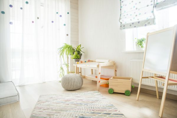 اتاق مهد کودک با صندلی و میز برای نقاشی اتاق کودک و مبلمان و گلهای سبز طبیعی روی طاقچه سفید