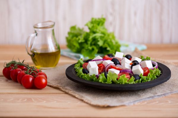 سالاد یونانی با سبزیجات تازه روی زمینه چوبی پنیر فتا و زیتون سیاه عشق به مفهوم غذای خام سالم