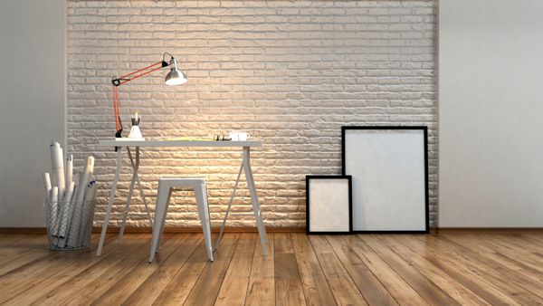استودیو یا ایستگاه کاری مدرن مینیمالیستی با یک لامپ زاویه‌دار که دیوار آجری بافت‌دار را روی میز طراحی یا نوشتن با رول‌هایی از طرح‌ها در کنار قاب‌های عکس خالی و رندر سه‌بعدی روشن می‌کند