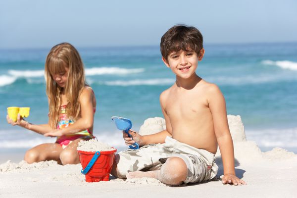 کودکان در تعطیلات ساحلی قلعه های شنی می سازند