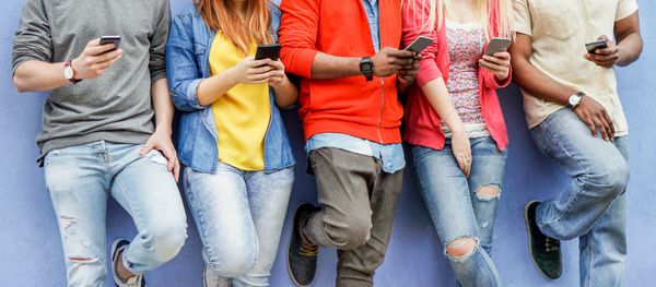 گروهی از دانشجویان چند نژادی در حال تماشای تلفن های همراه هوشمند در تعطیلات دانشگاهی - اعتیاد جوانان به روندهای فناوری جدید - لحظه بیگانگی برای مشکل نسل جدید - تمرکز بر دست های مرکزی