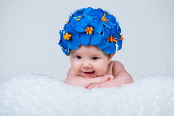 دختر تازه متولد شده خندان با کلاهی از گلهای آبی پامچال