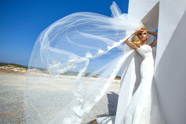مدل زن عروس زیبا در ژست های شگفت انگیز لباس عروس در جزیره سانتورینی یونان و فراتر از آن منظره ای زیبا است