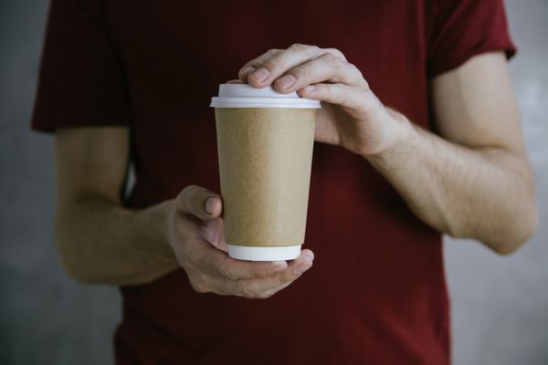 دست‌های مرد که فنجان قهوه کاغذی سفید را برای برداشتن در دست دارند ماکت فنجان قهوه کارتنی تمیز ماکت افقی پس‌زمینه بسته