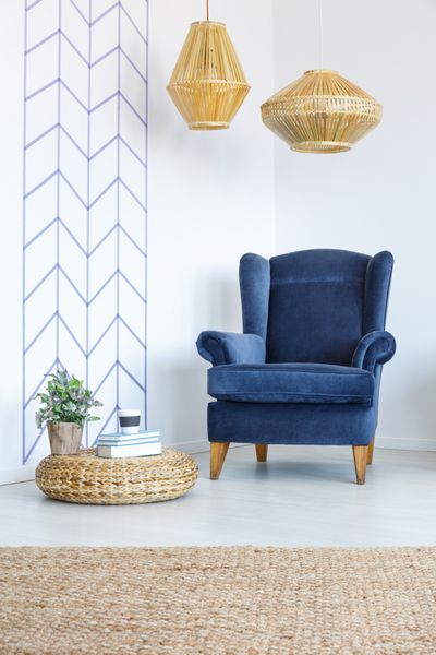 اتاق سفید با نوار دیواری تزئینی صندلی راحتی آبی لامپ پوف
